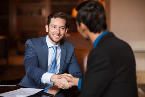 Two professionals shake hands because one of them has been promoted